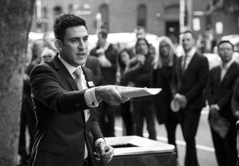 Auctioneer calling a Ray White auction in front of a crowd of bidders
